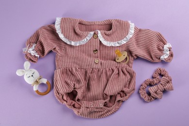 Flat lay composition with baby clothes and accessories on violet background