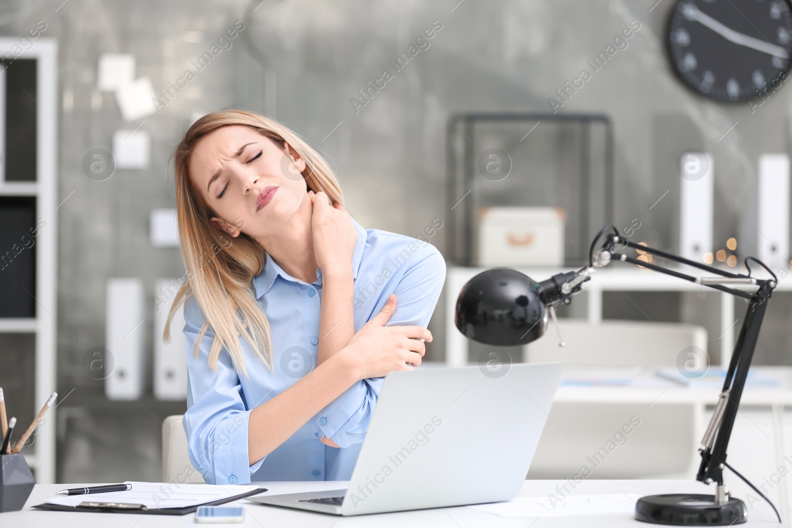 Photo of Young woman suffering from neck pain in office