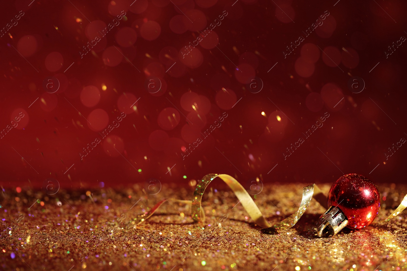 Photo of Golden glitter, Christmas ball and streamer against color background. Space for text