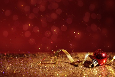 Golden glitter, Christmas ball and streamer against color background. Space for text