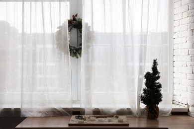 Photo of Cooking cutters and decorative Christmas tree on wooden table indoors