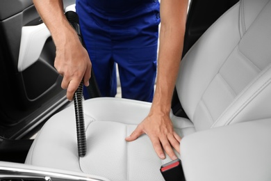 Photo of Man using vacuum cleaner in auto, closeup. Car wash