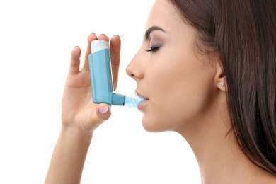 Image of Young woman using asthma inhaler on white background