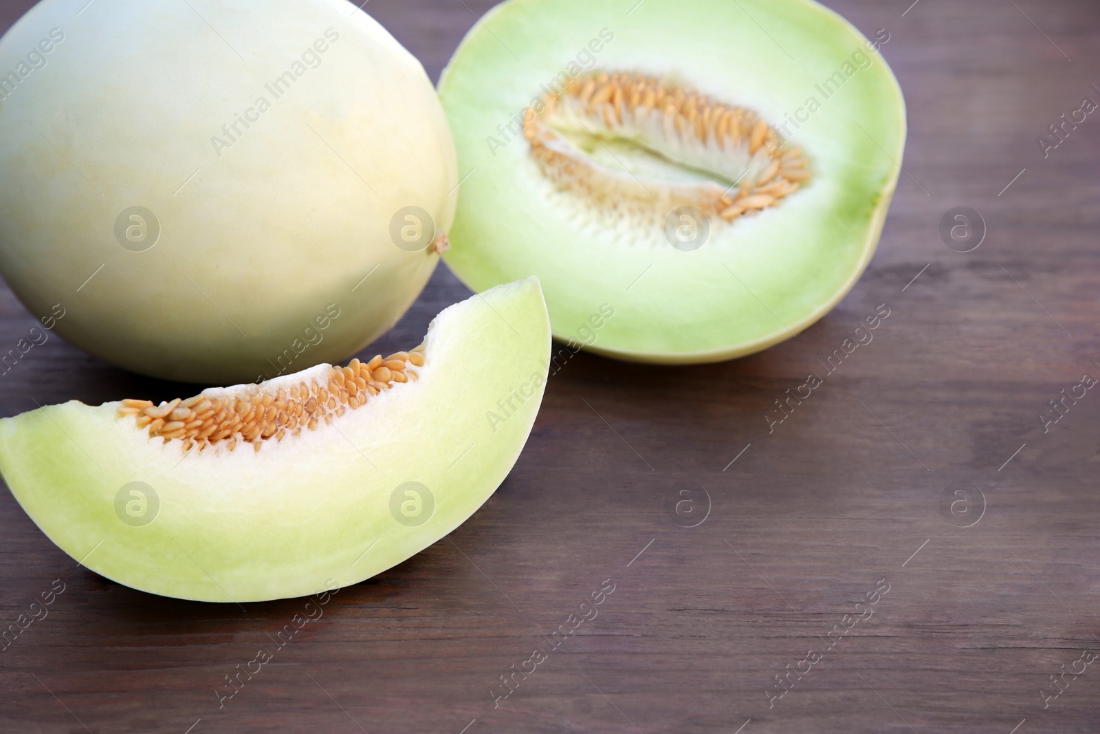 Photo of Tasty whole and cut ripe melons on wooden table