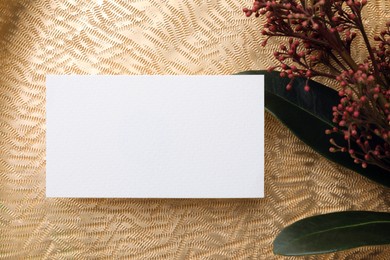 Photo of Blank business card and beautiful plant with green leaves on golden background, flat lay. Mockup for design