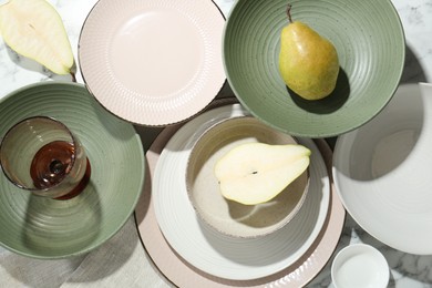 Photo of Stylish ceramic plates, glass and pears on white marble table, flat lay