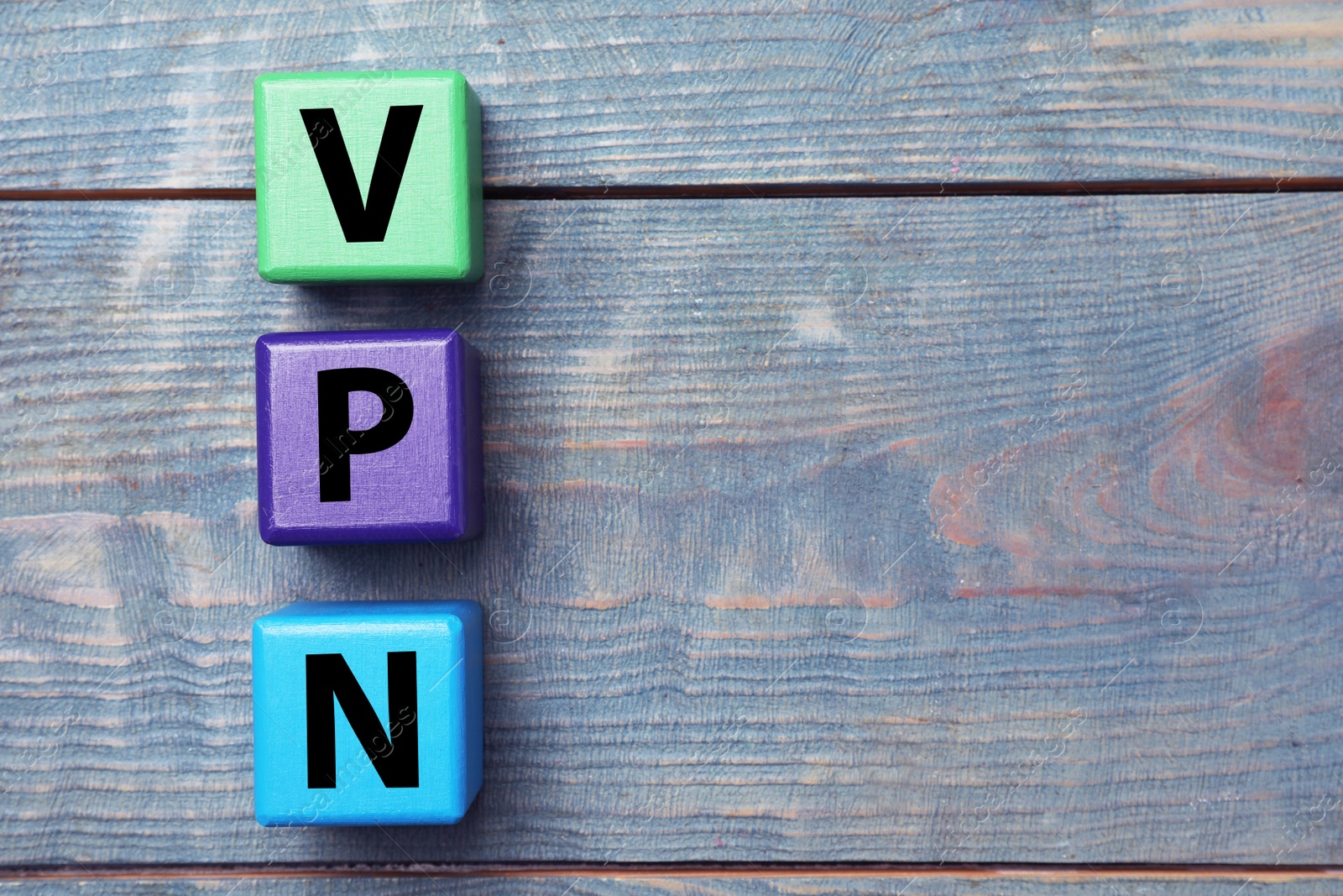 Image of Color cubes with acronym VPN on blue wooden background, flat lay. Space for text