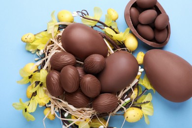 Photo of Delicious chocolate eggs on light blue background, flat lay
