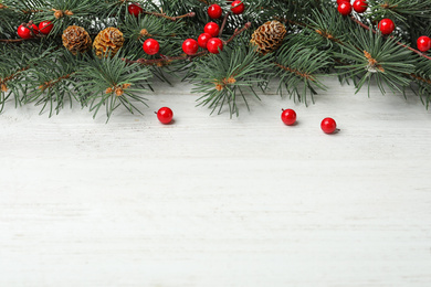 Photo of Composition with fir branches and berries on white wooden background, space for text. Winter holidays