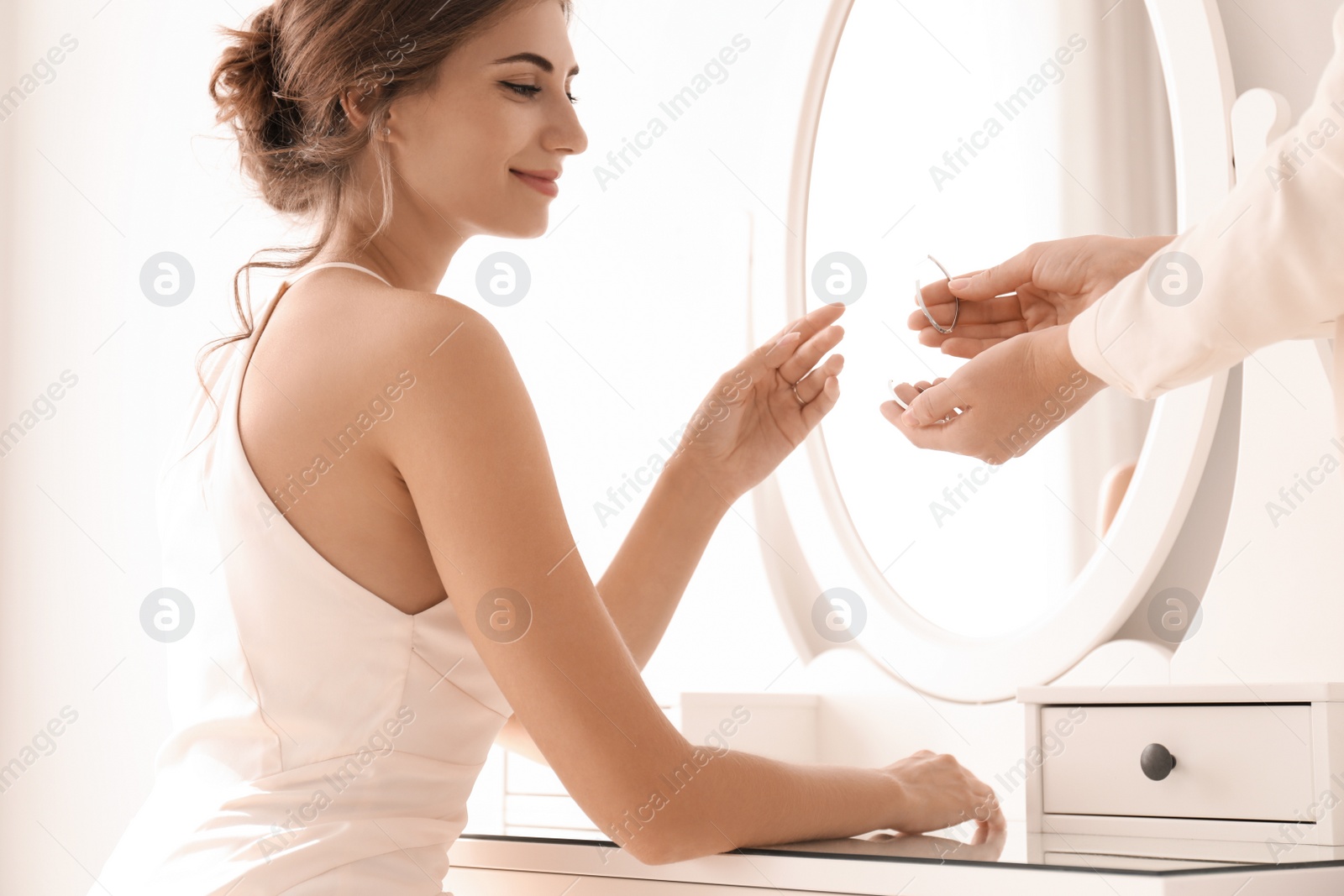 Photo of Woman helping bride to get ready for her wedding indoors