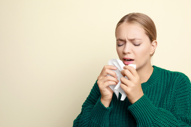 Image of Young woman sneezing on light background, space for text. Cold symptoms