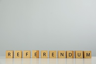 Photo of Word Referendum of wooden cubes on table against light grey background. Space for text