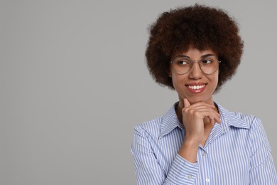 Portrait of happy young woman in eyeglasses on grey background. Space for text