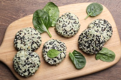 Photo of Tasty vegan cutlets with sesame seeds and spinach on wooden table, top view
