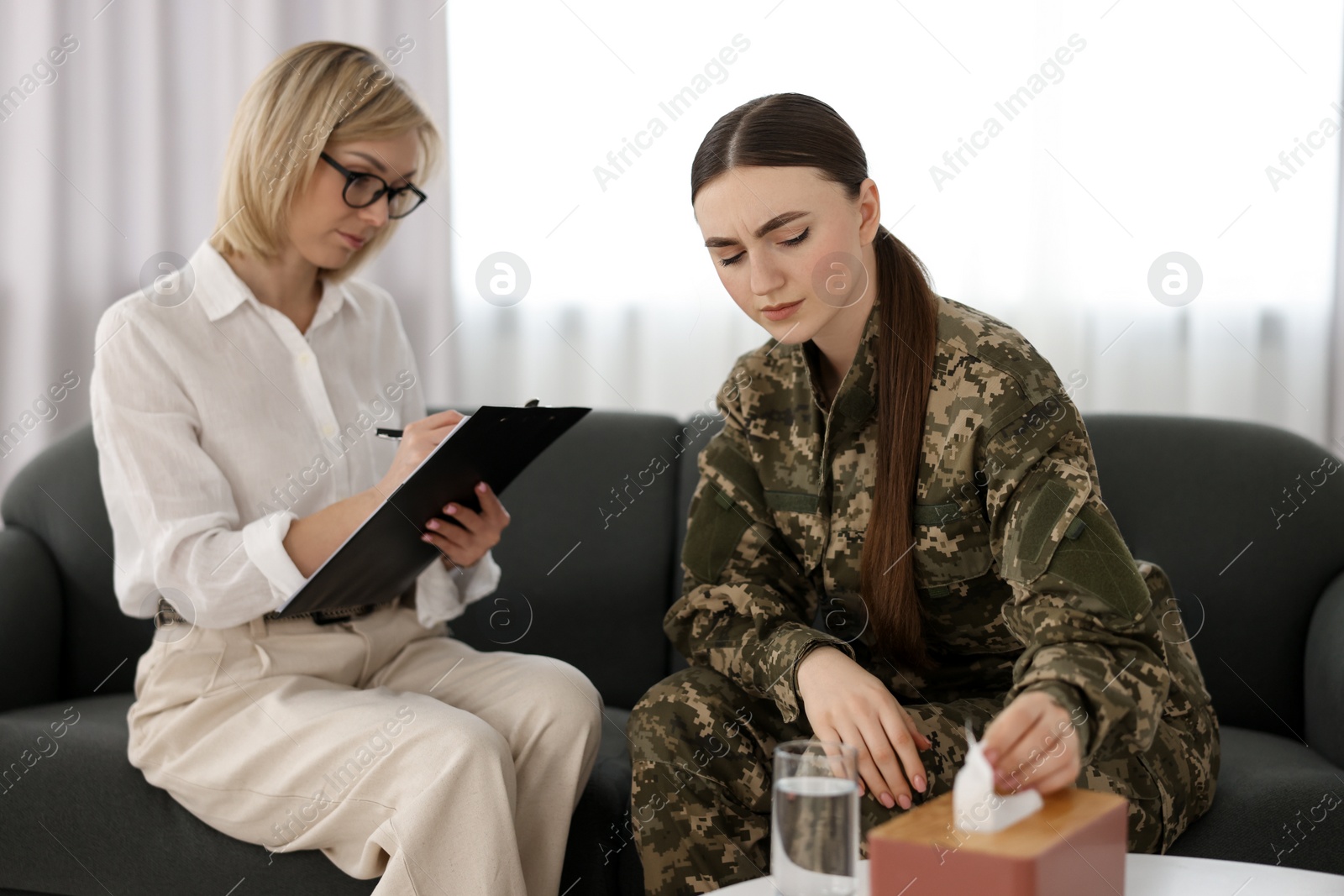 Photo of Psychotherapist working with military woman on sofa in office