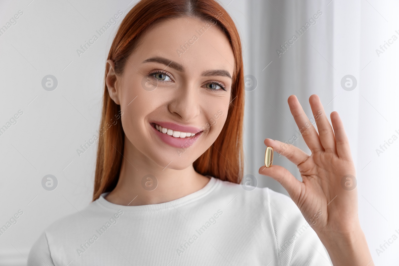 Photo of Beautiful young woman with vitamin pill at home