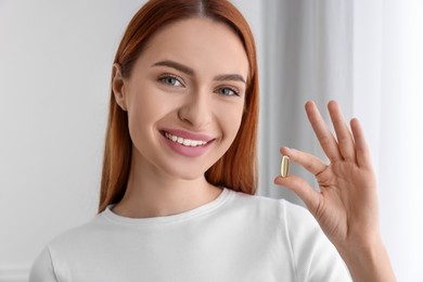 Photo of Beautiful young woman with vitamin pill at home