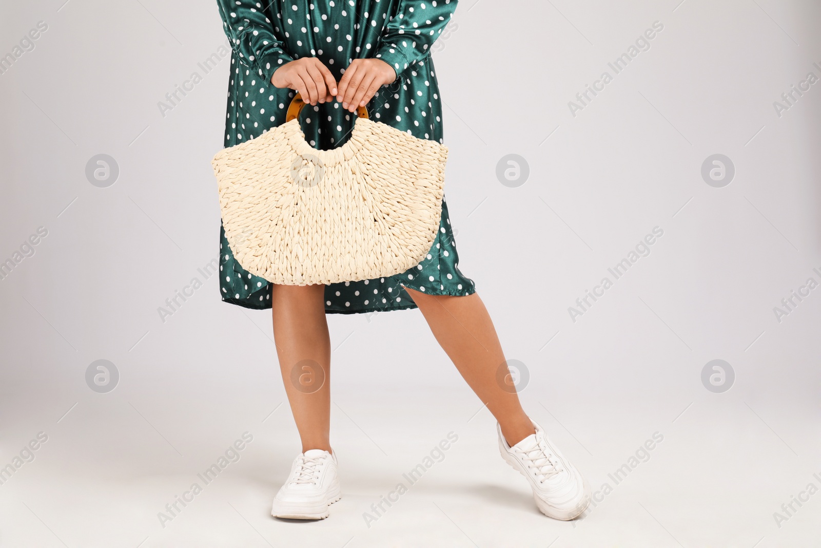 Photo of Young woman with stylish straw bag on light grey background, closeup