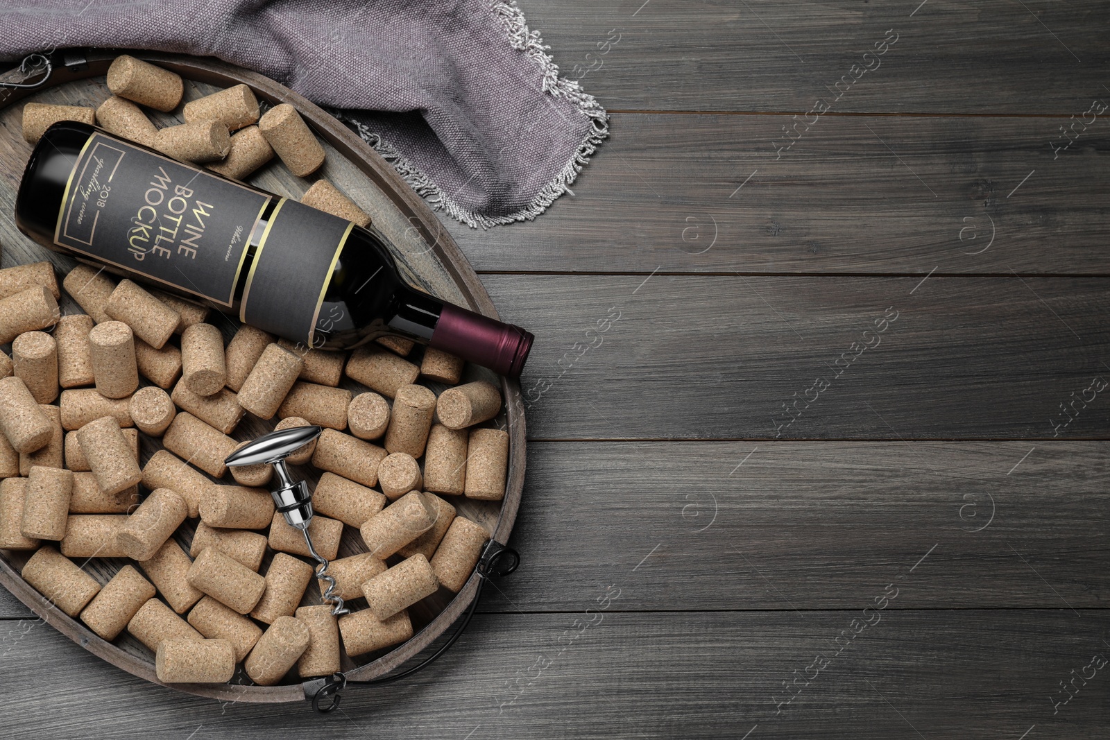 Photo of Tray with corkscrew, wine bottle and stoppers on wooden table, flat lay. Space for text