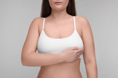 Mammology. Woman doing breast self-examination on light grey background, closeup