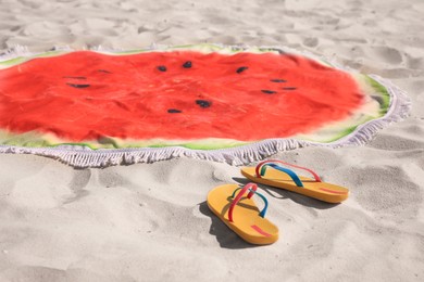 Flip flops and watermelon beach towel with tassels on sand