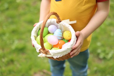 Easter celebration. Little boy holding basket with painted eggs outdoors, closeup