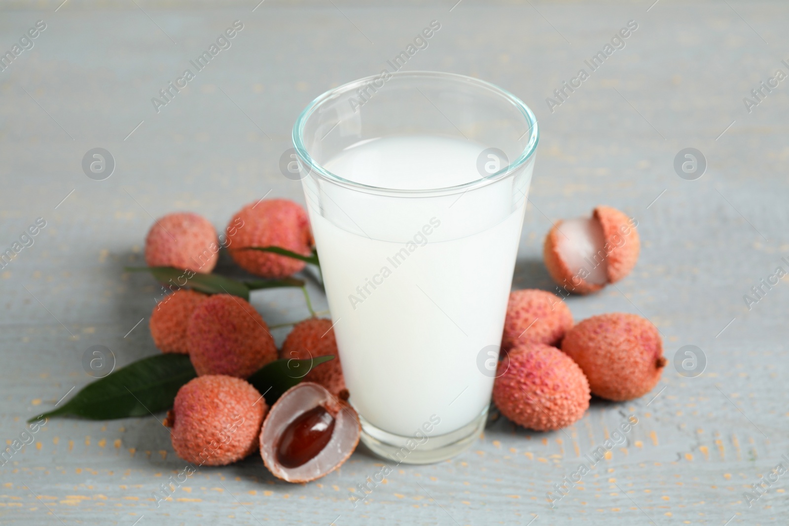 Photo of Fresh lychee juice and fruits on grey wooden table