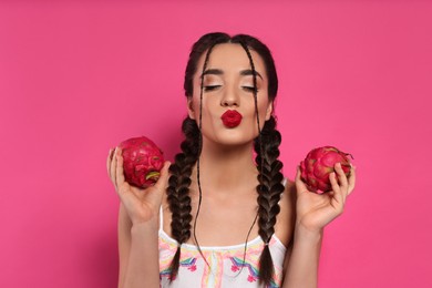 Young woman with fresh pitahayas on pink background. Exotic fruit