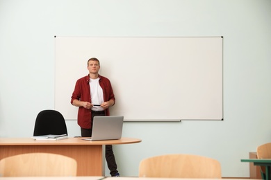 Male teacher near whiteboard in modern classroom