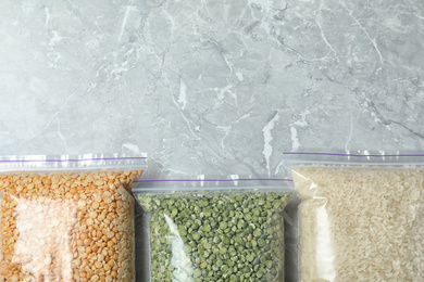 Photo of Different types of legumes and cereals on grey marble table, flat lay. Organic grains