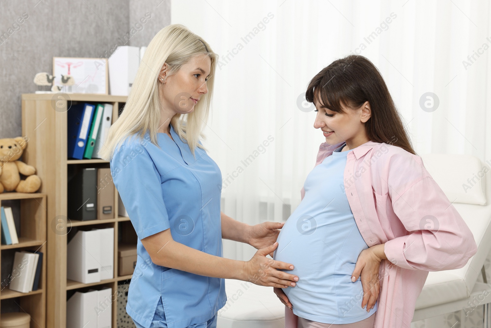 Photo of Pregnancy checkup. Doctor examining patient's tummy in clinic