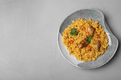 Plate of delicious rice pilaf on grey background, top view with space for text