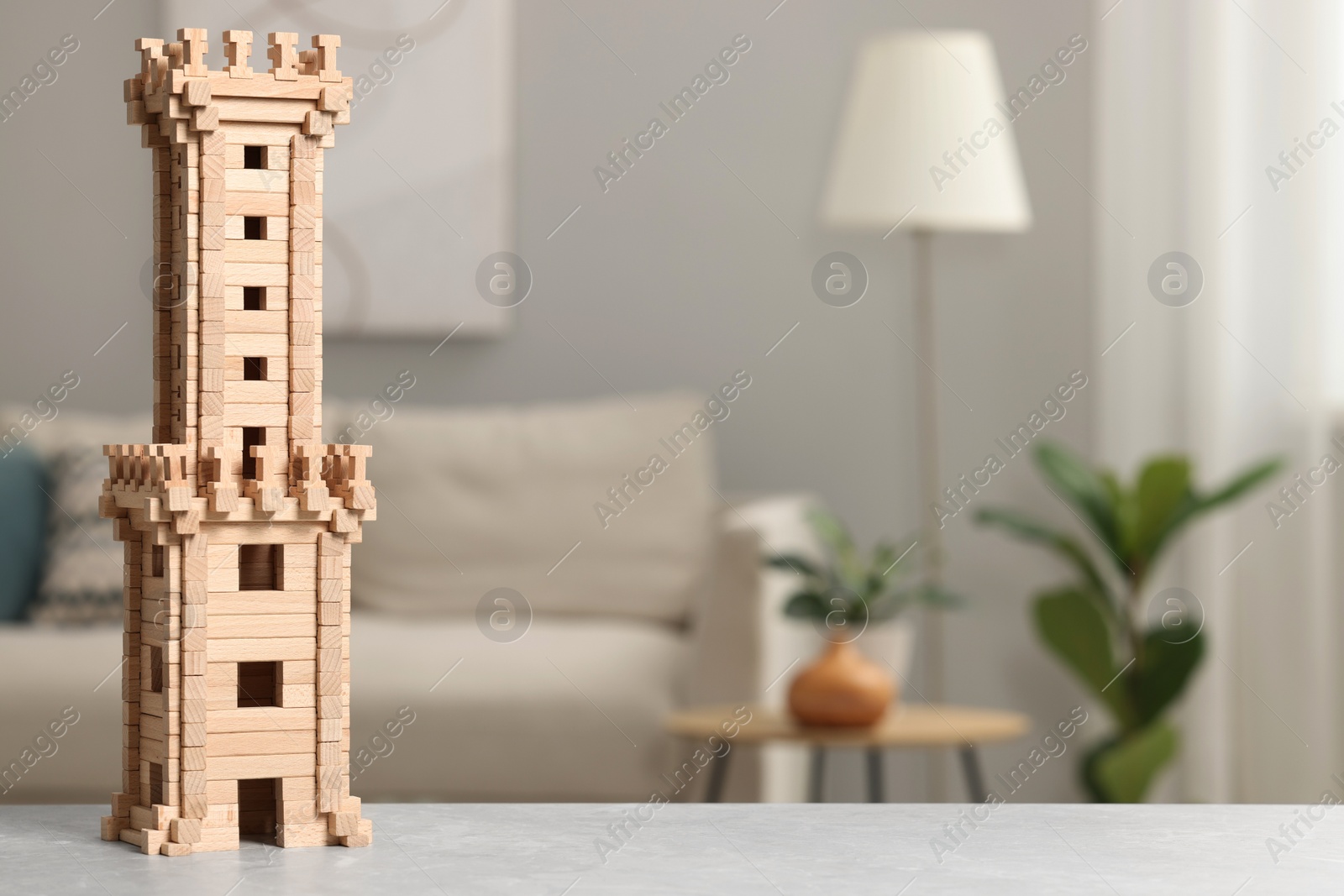 Photo of Wooden tower on light grey table indoors, space for text. Children's toy