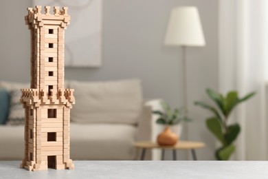 Wooden tower on light grey table indoors, space for text. Children's toy