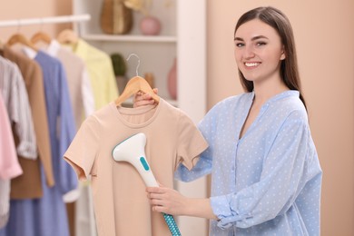 Photo of Woman steaming shirt on hanger at home