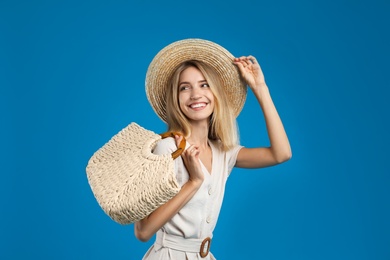 Photo of Beautiful young woman with stylish straw bag on blue background