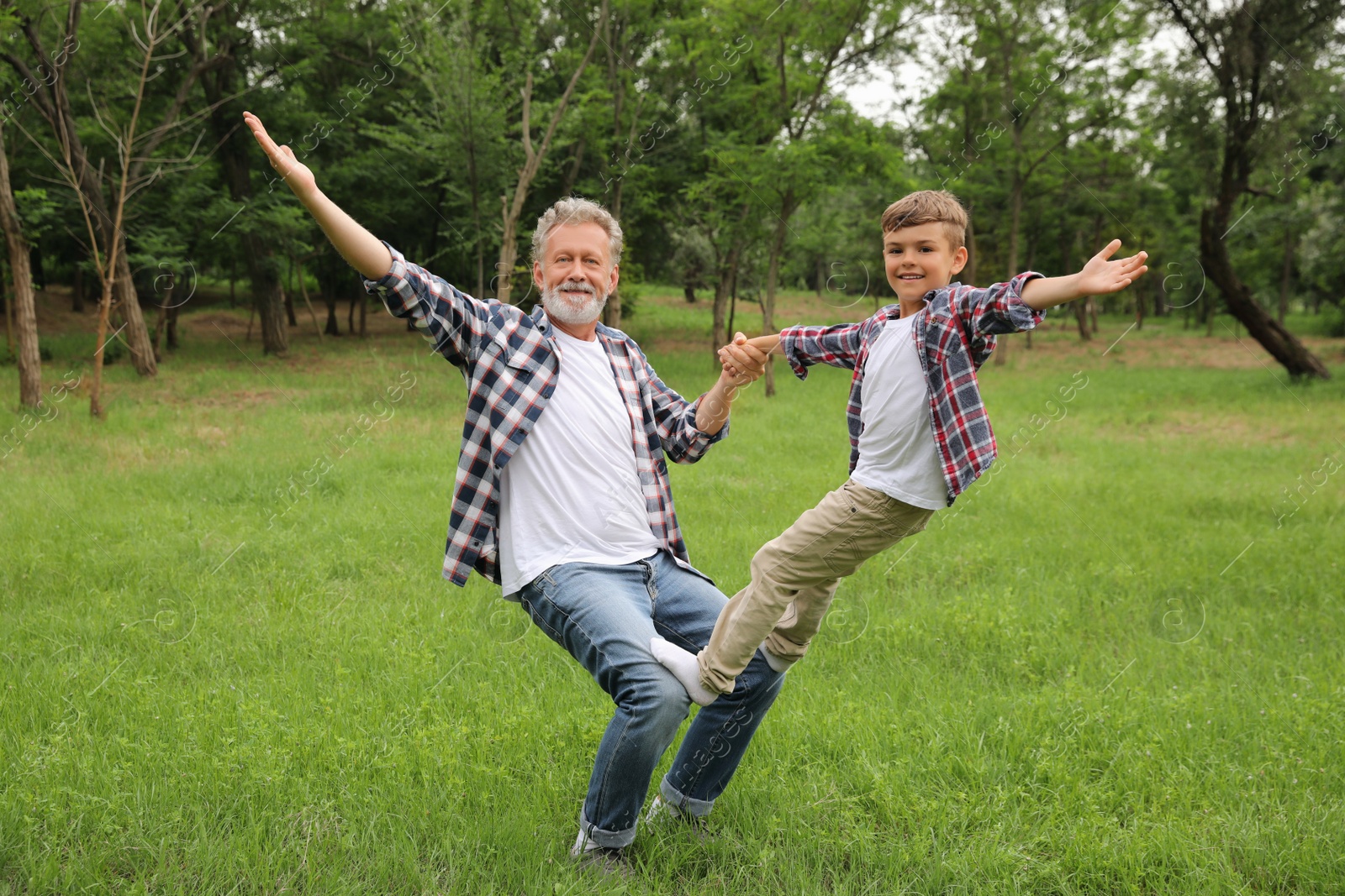 Photo of Cute little boy playing with grandfather in park