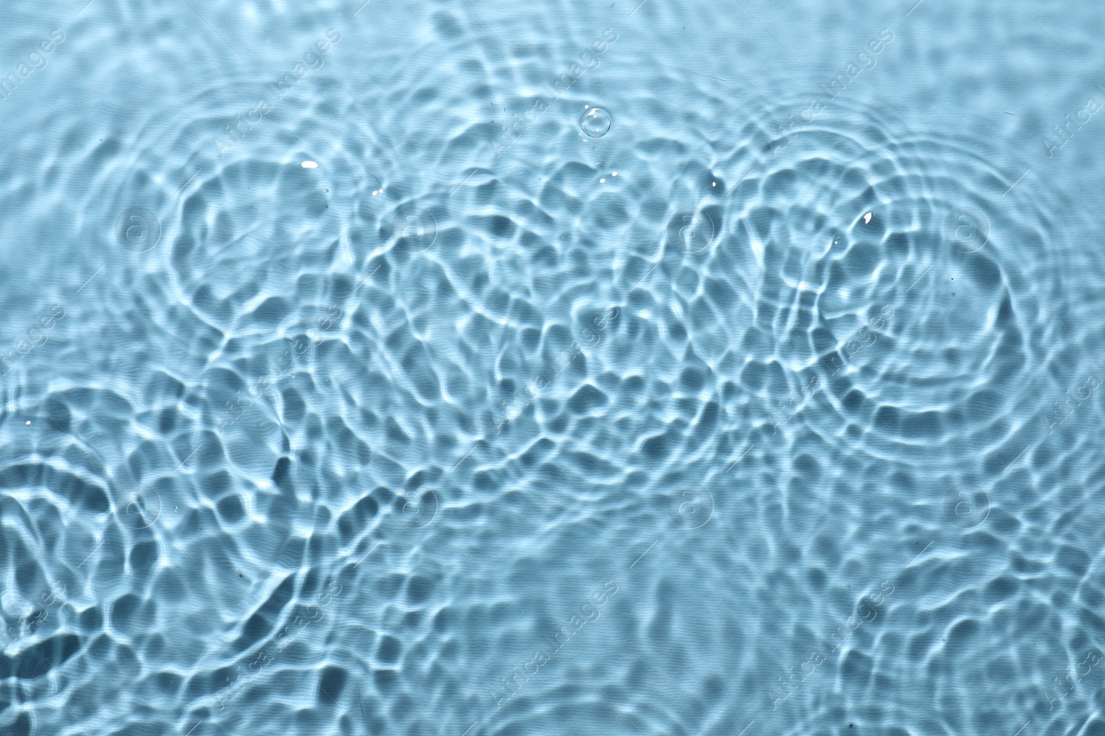 Photo of Rippled surface of clear water on light blue background, top view