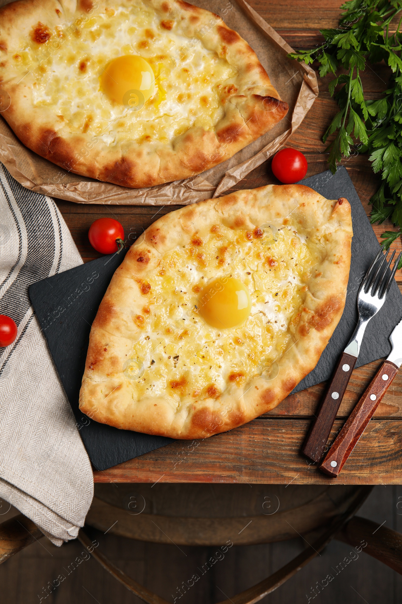 Photo of Fresh delicious Adjarian khachapuris served on wooden table, flat lay