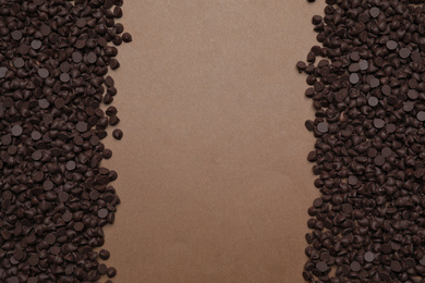 Photo of Delicious chocolate chips on brown background, top view. Space for text