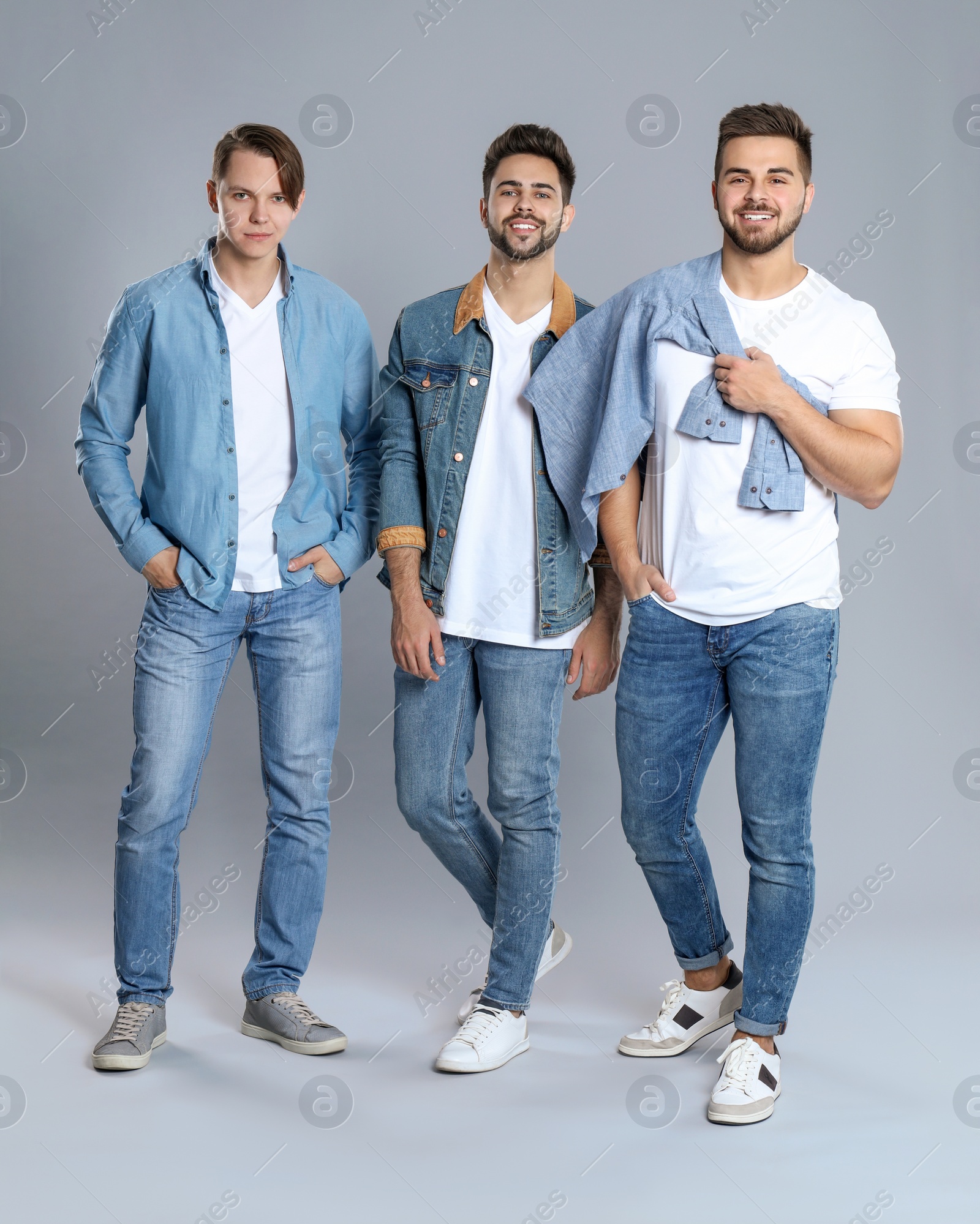 Photo of Group of young men in stylish jeans on grey background