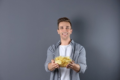 Photo of Man with bowl of potato chips on grey background