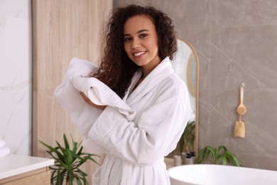 Photo of Beautiful African American woman drying hair with towel in bathroom