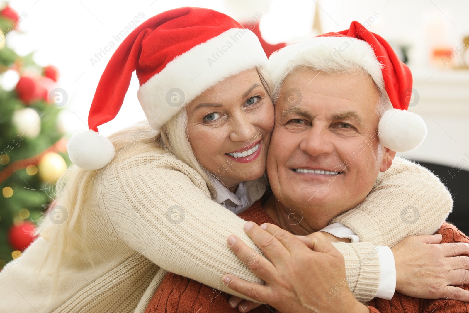 Photo of Happy mature couple in Santa hats at home. Christmas celebration