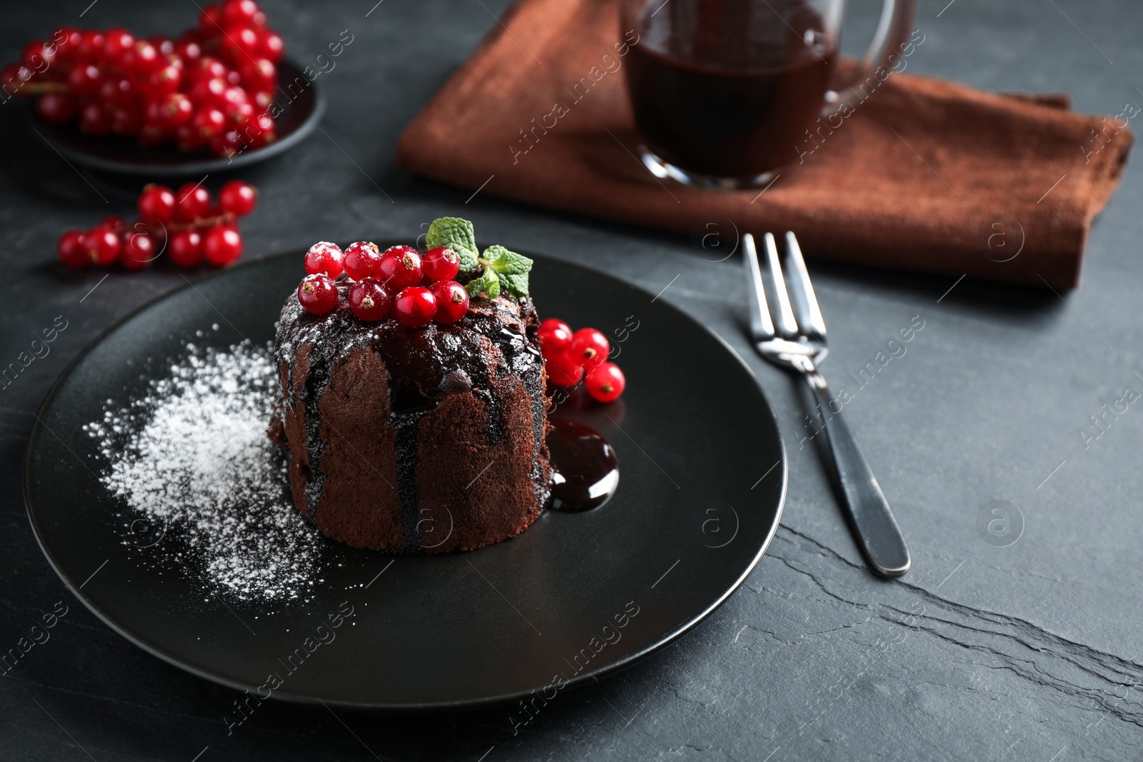 Photo of Delicious warm chocolate lava cake with mint and berries on dark grey table