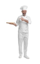 Photo of Happy chef in uniform pointing at wooden board on white background