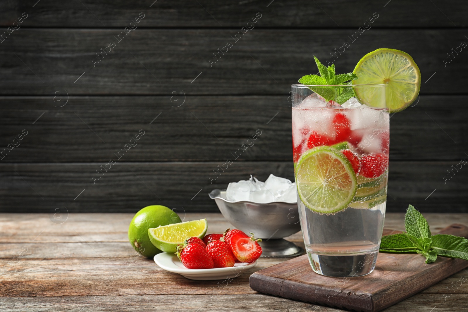 Photo of Glass of natural lemonade with lime, strawberries and mint on table