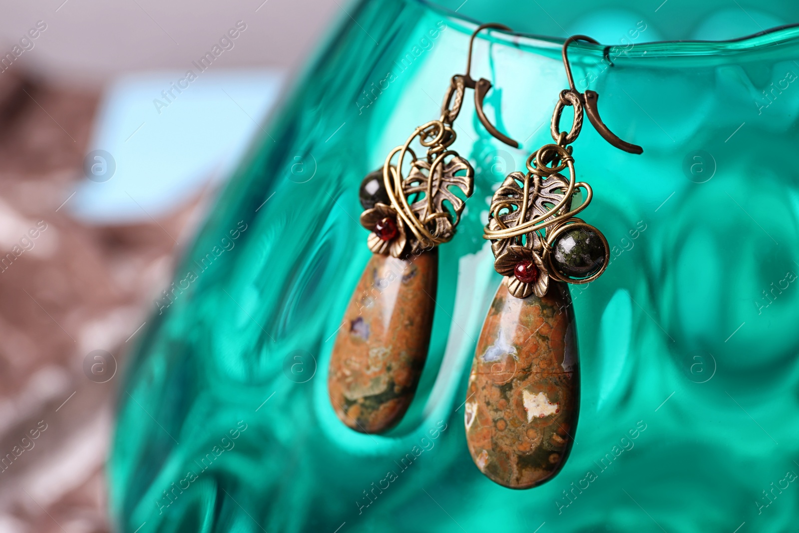 Photo of Beautiful pair of metal earrings with jasper gemstones on glass stand