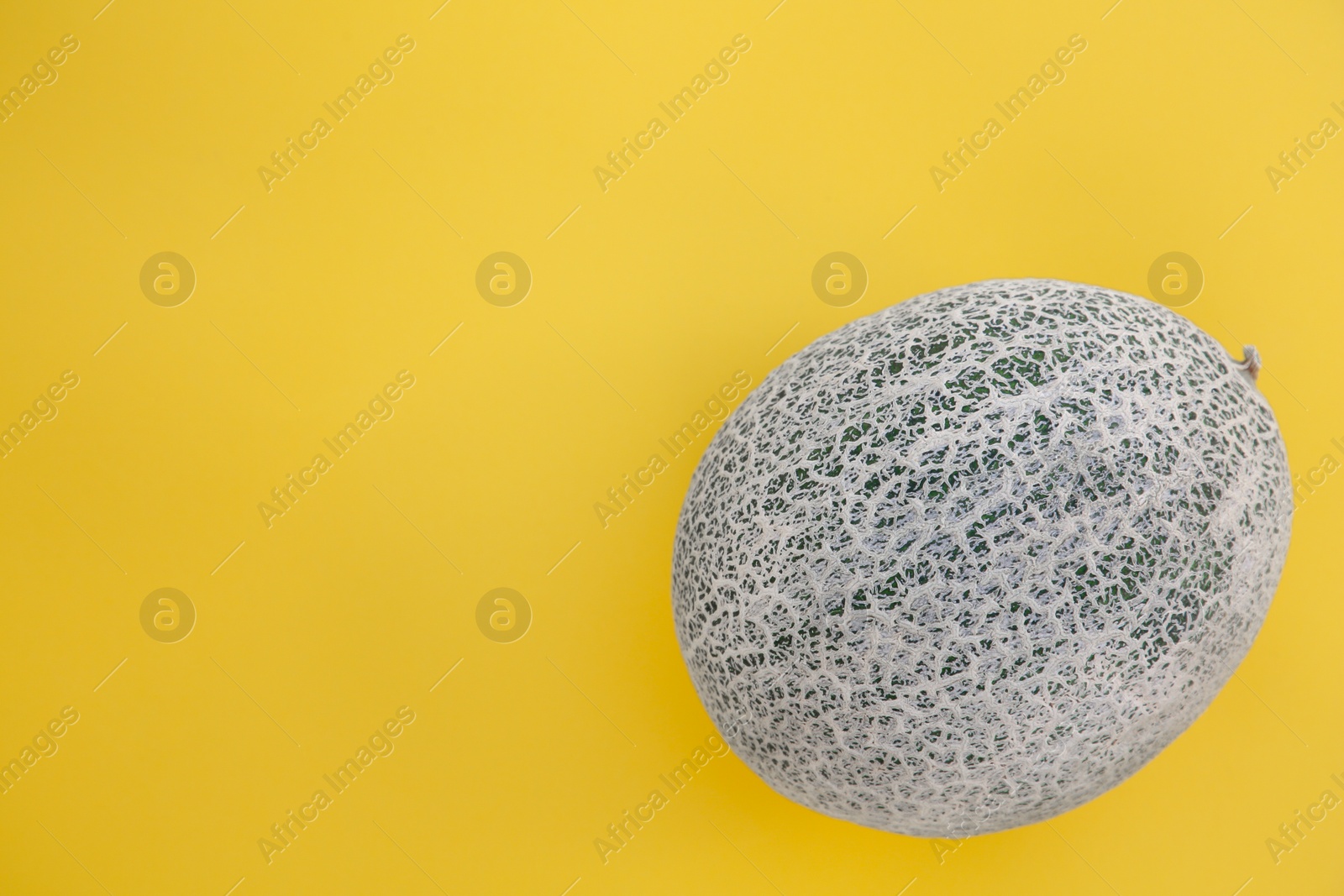 Photo of Whole fresh ripe cantaloupe melon on yellow background, top view. Space for text