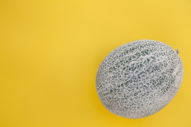 Whole fresh ripe cantaloupe melon on yellow background, top view. Space for text